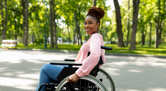 Image d’une jeune femme souriante en fauteuil roulant à l’extérieur